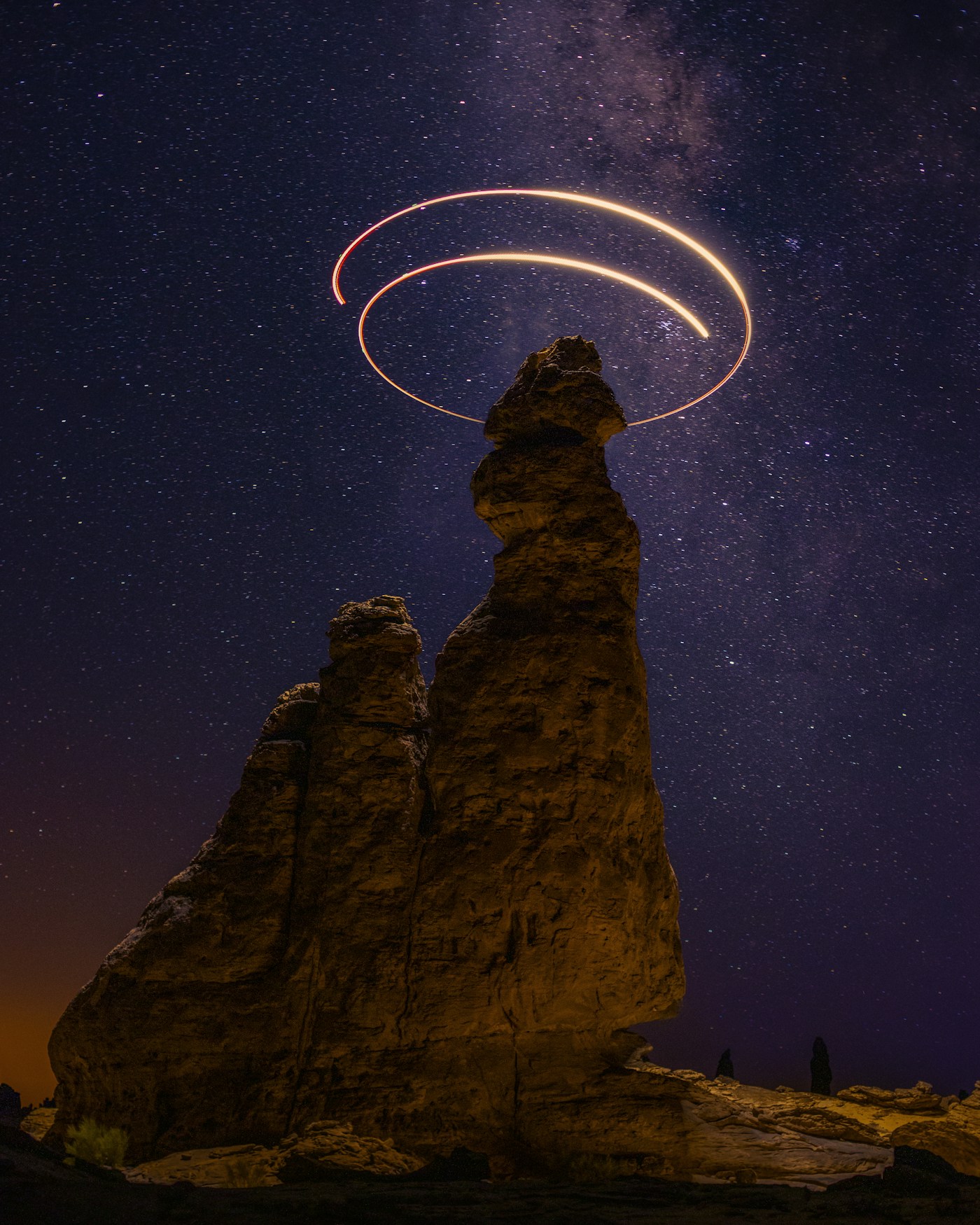 Creative long-exposure image with light painting between AlUla rocks beneath a starry sky
