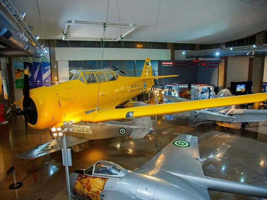 A yellow historic aircraft displayed inside Saqer Al Jazirah Aviation Museum